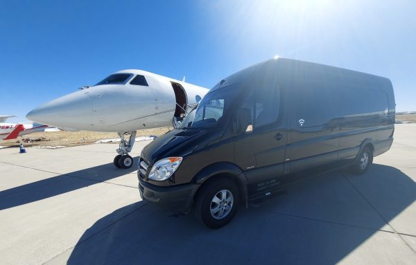 A van and an airplane are parked on the tarmac.
